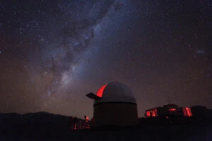 View of milky way with observatory in foreground at top of Mt John