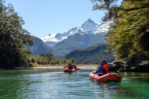 Pair of inflatable canoes paddling towards a snowcapped mountain 